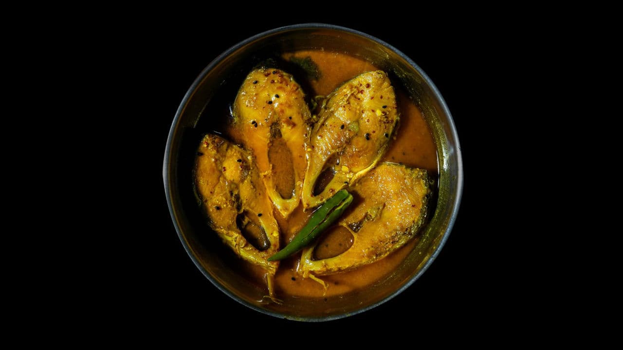 Fish curry in a bowl on black background